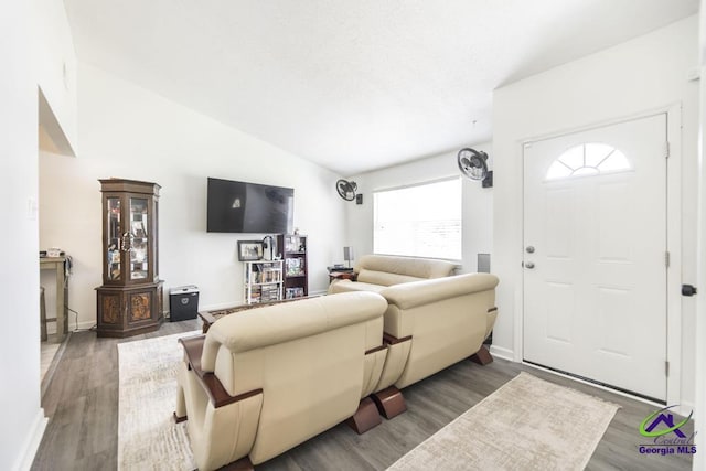 living room featuring wood finished floors, lofted ceiling, and baseboards
