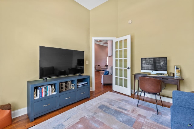 home office featuring baseboards, wood finished floors, french doors, and a high ceiling