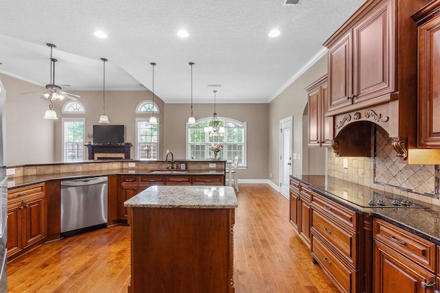 kitchen featuring stainless steel dishwasher, a kitchen island, a fireplace, a sink, and ceiling fan