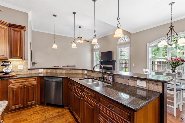 kitchen featuring dishwasher, a sink, ornamental molding, light wood-style flooring, and decorative light fixtures