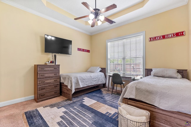 carpeted bedroom with a tray ceiling, ornamental molding, baseboards, and ceiling fan