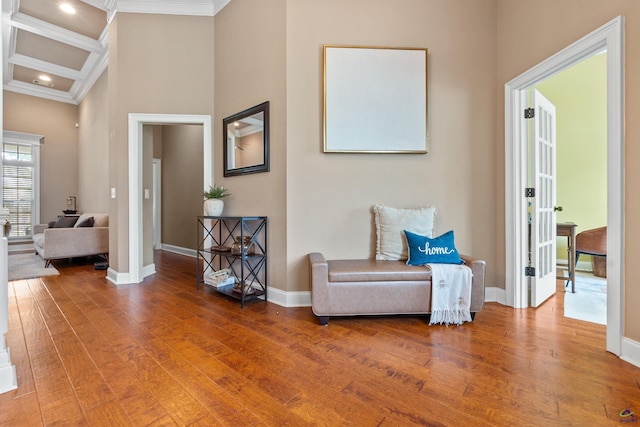 sitting room with ornamental molding, wood finished floors, baseboards, a towering ceiling, and beam ceiling