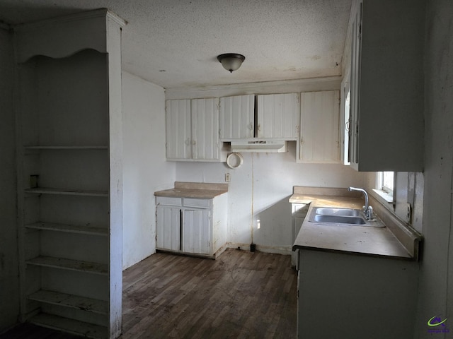 kitchen with a sink, dark wood finished floors, white cabinetry, a textured ceiling, and baseboards