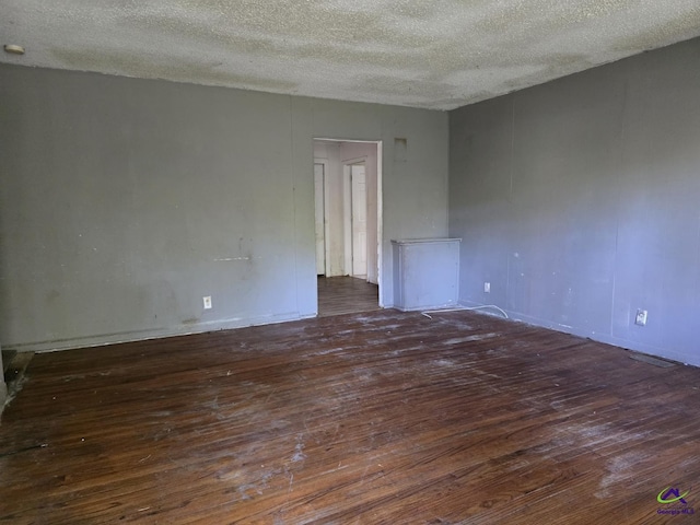 spare room featuring a textured ceiling, wood-type flooring, and baseboards