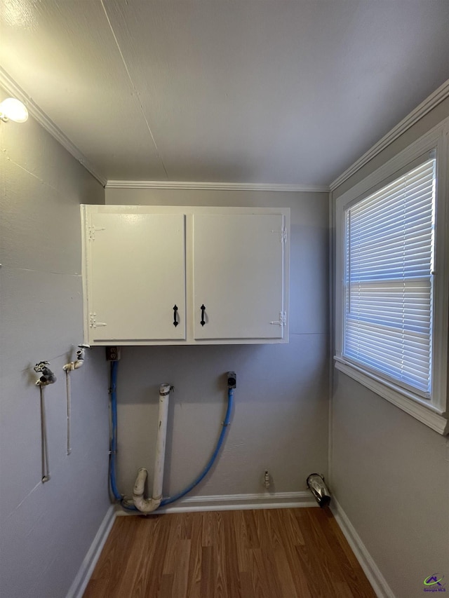 laundry room featuring cabinet space, wood finished floors, baseboards, electric dryer hookup, and ornamental molding