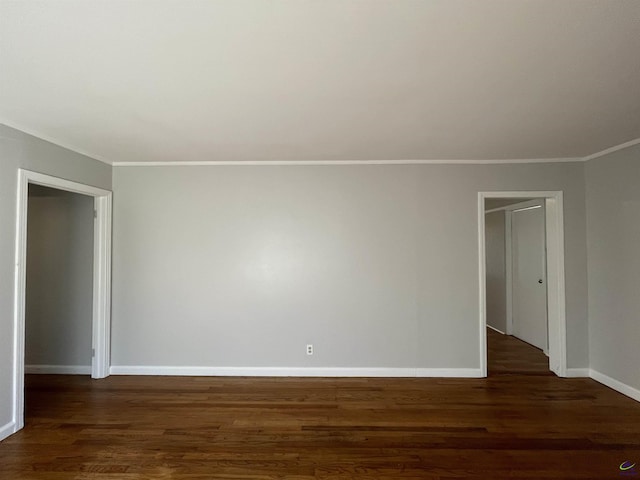 unfurnished room featuring crown molding, dark wood finished floors, and baseboards