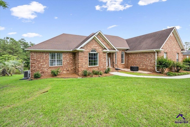 view of front of home with brick siding, a front yard, cooling unit, and a shingled roof