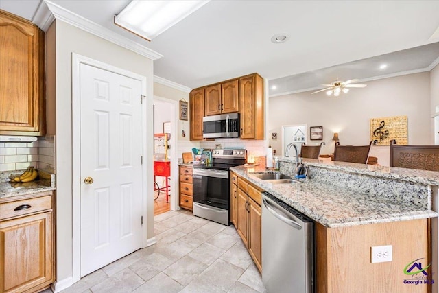 kitchen featuring stainless steel appliances, a sink, a ceiling fan, backsplash, and ornamental molding
