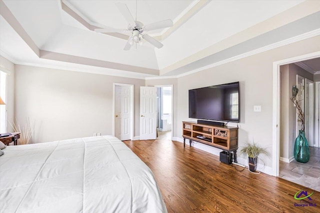 bedroom with a raised ceiling, multiple windows, wood finished floors, and crown molding