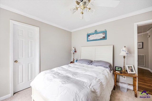 bedroom with carpet, ornamental molding, baseboards, attic access, and a ceiling fan