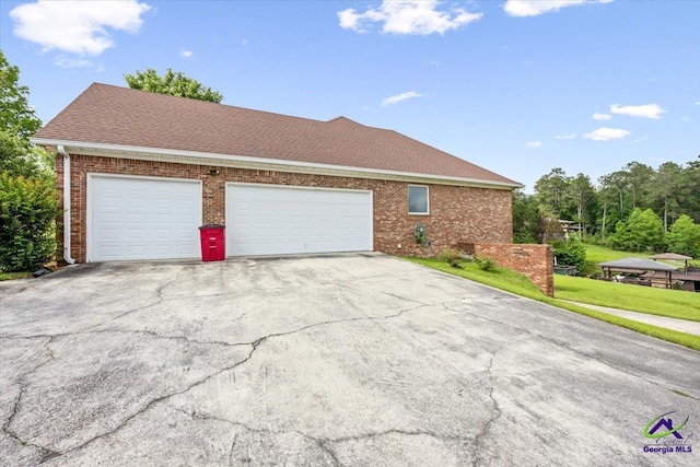 view of property exterior with brick siding, asphalt driveway, an attached garage, and a shingled roof