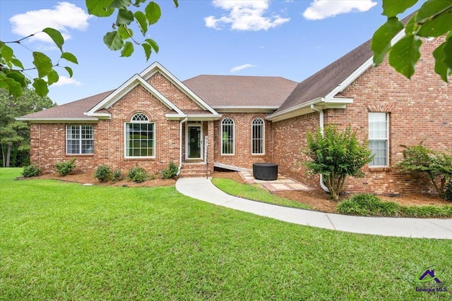 view of front of home with brick siding, a front lawn, and roof with shingles