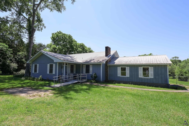 single story home featuring a front lawn, metal roof, a chimney, and board and batten siding