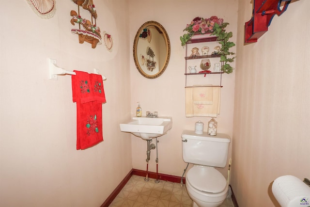 half bathroom featuring toilet, baseboards, and tile patterned floors