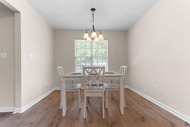 dining area with wood finished floors, baseboards, a chandelier, and a textured ceiling