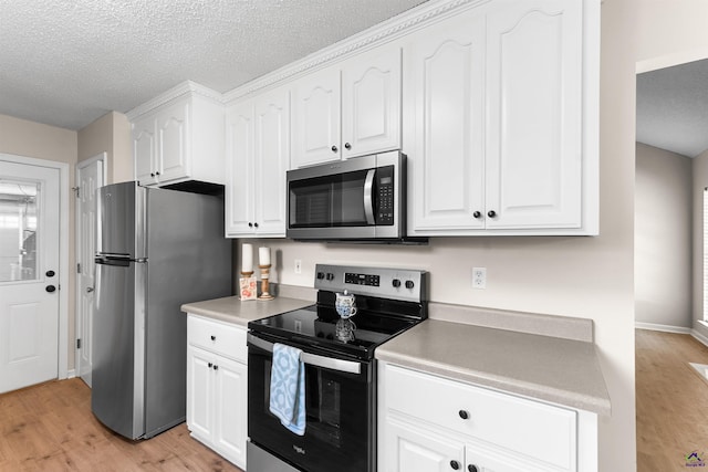 kitchen with appliances with stainless steel finishes, light wood-type flooring, white cabinets, a textured ceiling, and light countertops