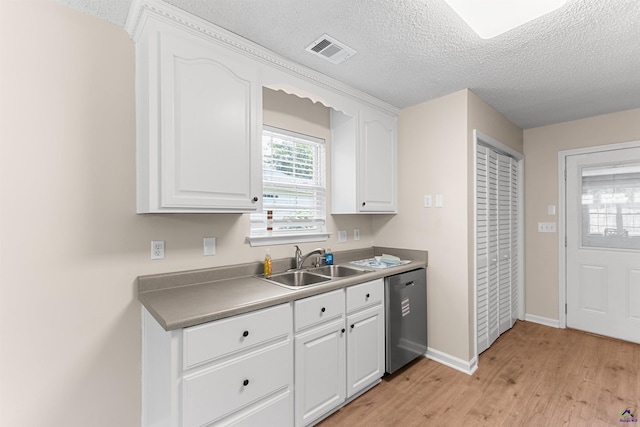 kitchen featuring dishwasher, a sink, light wood-style flooring, white cabinets, and a textured ceiling