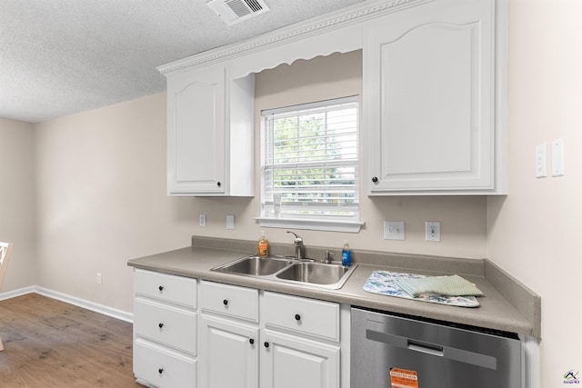 kitchen featuring a sink, dishwasher, light wood-style floors, white cabinets, and a textured ceiling