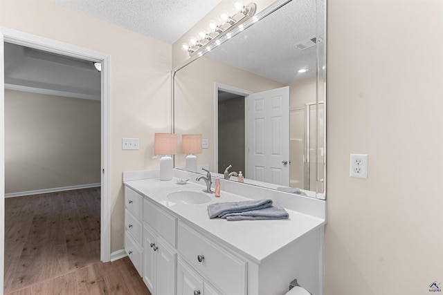 bathroom featuring a textured ceiling, vanity, wood finished floors, and baseboards