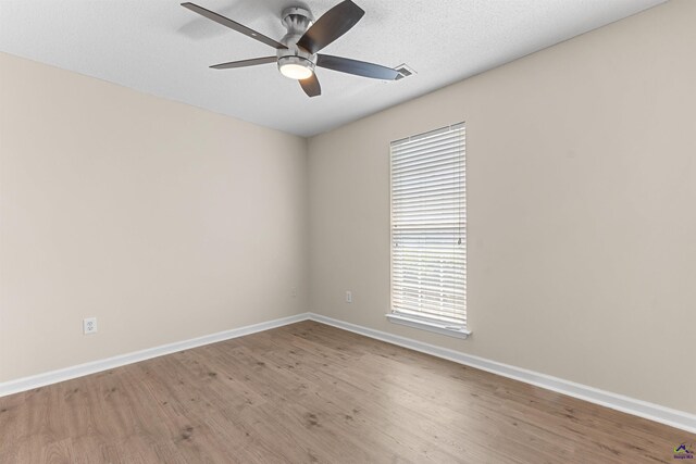 empty room with wood finished floors, a ceiling fan, and baseboards
