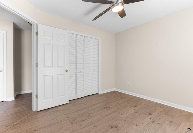 unfurnished bedroom featuring baseboards, wood finished floors, a closet, and a ceiling fan