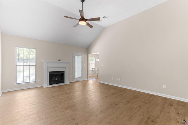 unfurnished living room with ceiling fan, light wood-style floors, a fireplace, baseboards, and high vaulted ceiling