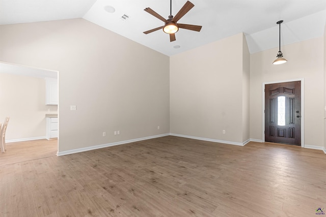 foyer entrance with high vaulted ceiling, ceiling fan, light wood-style flooring, and baseboards