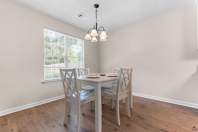 dining room with baseboards, a chandelier, wood finished floors, and a textured ceiling