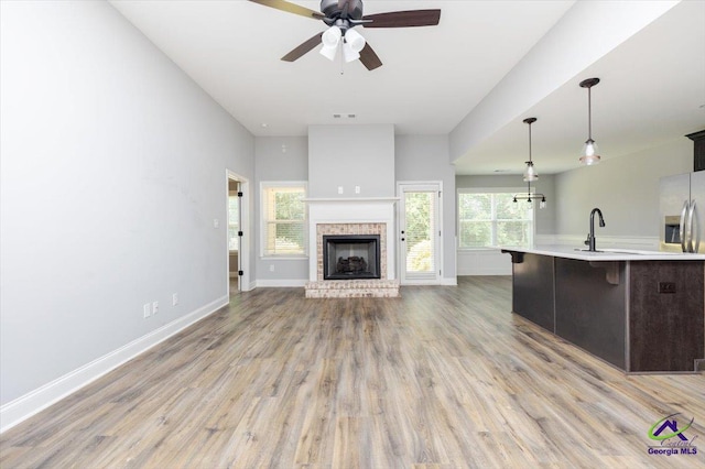 136 Sourwood Ln, Centerville, GA 31093 - unfurnished living room featuring a ceiling fan, light wood-type flooring, a sink, baseboards, and a fireplace