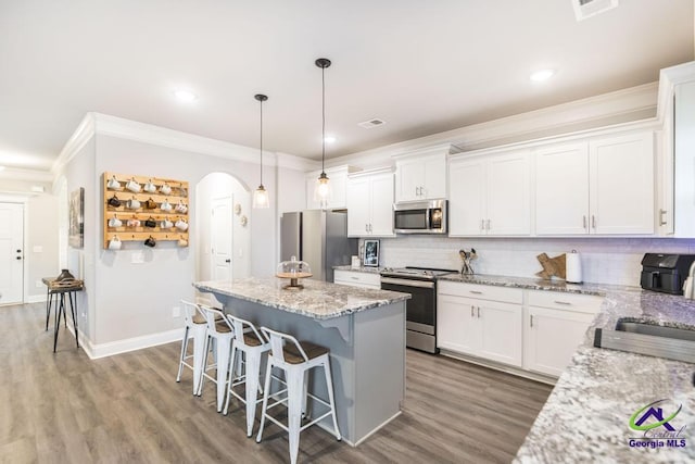 321 Harley Farms Dr, Bonaire, GA 31005 - kitchen with stainless steel appliances, a kitchen island, ornamental molding, a kitchen breakfast bar, and arched walkways