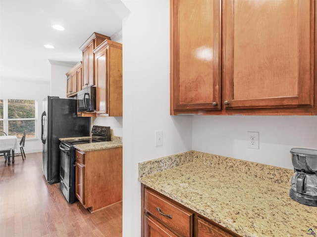 427 Oscar Ct, Mcdonough, GA 30252 - kitchen with black range with electric cooktop, light wood-style floors, light stone countertops, brown cabinetry, and recessed lighting