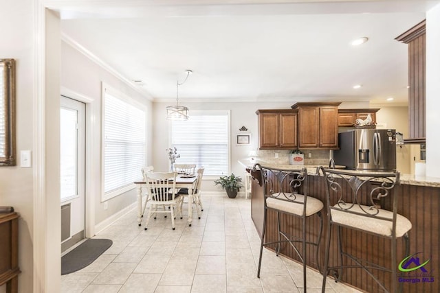 215 Wilson Creek Bnd, Bonaire, GA 31005 - kitchen with stainless steel refrigerator with ice dispenser, brown cabinetry, baseboards, ornamental molding, and tasteful backsplash