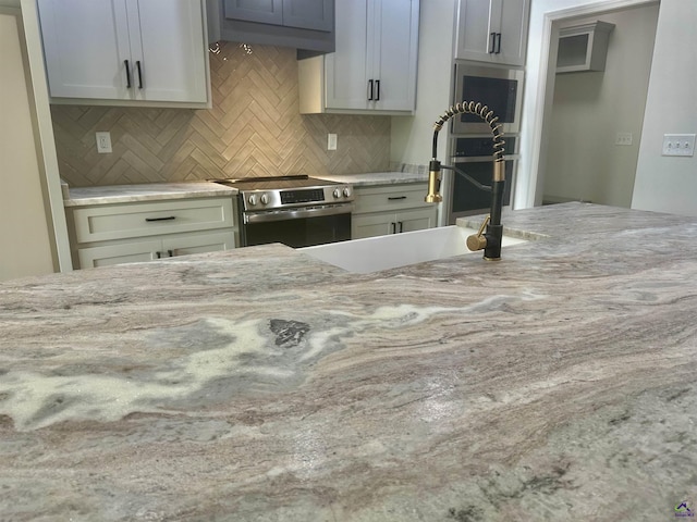 86 Camden Way, Hawkinsville, GA 31036 - kitchen with stainless steel range with electric stovetop, a sink, decorative backsplash, and light stone countertops