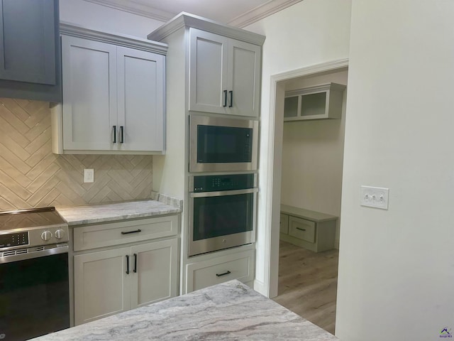 86 Camden Way, Hawkinsville, GA 31036 - kitchen featuring stainless steel appliances, backsplash, light wood finished floors, light stone counters, and crown molding
