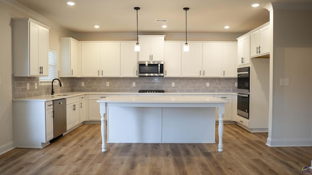 303 Garnet Dr, Bonaire, GA 31005 - kitchen with appliances with stainless steel finishes, a sink, a kitchen island, wood finished floors, and light countertops