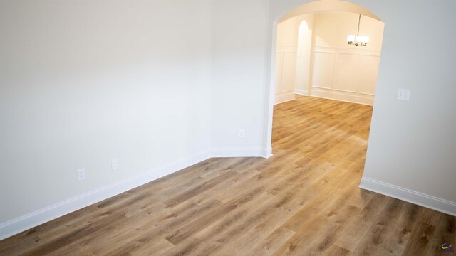 303 Garnet Dr, Bonaire, GA 31005 - empty room featuring arched walkways, light wood-style floors, and baseboards