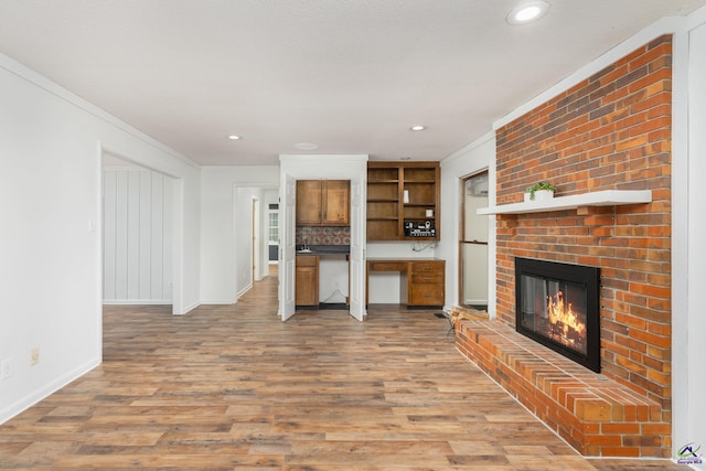 207 Oak Forest Ln, Warner Robins, GA 31088 - unfurnished living room with a brick fireplace, wood finished floors, baseboards, crown molding, and recessed lighting