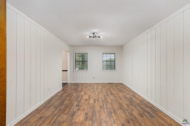 207 Oak Forest Ln, Warner Robins, GA 31088 - spare room with dark wood finished floors, a textured ceiling, wood walls, and baseboards