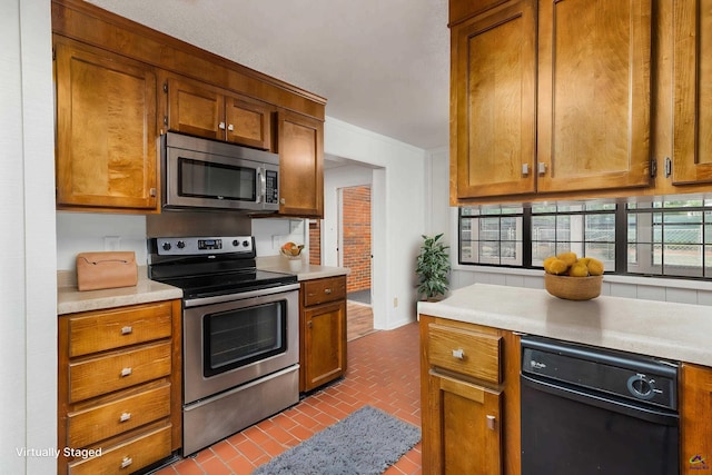 207 Oak Forest Ln, Warner Robins, GA 31088 - kitchen featuring appliances with stainless steel finishes, brick floors, light countertops, and brown cabinets