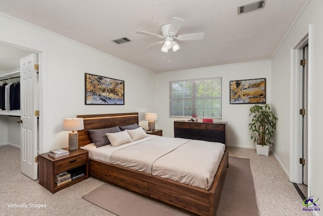 207 Oak Forest Ln, Warner Robins, GA 31088 - bedroom with light carpet, a spacious closet, a textured ceiling, ornamental molding, and a ceiling fan