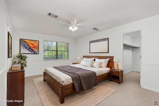 207 Oak Forest Ln, Warner Robins, GA 31088 - bedroom with light colored carpet, a walk in closet, baseboards, and a textured ceiling