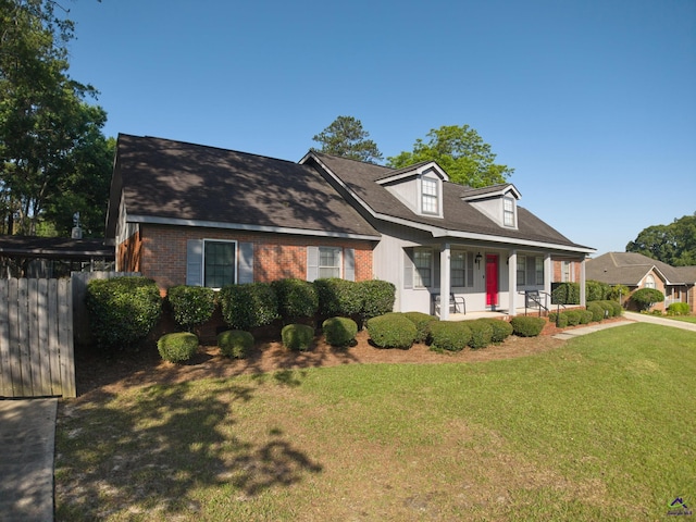 207 Oak Forest Ln, Warner Robins, GA 31088 - new england style home with covered porch, a front lawn, and brick siding