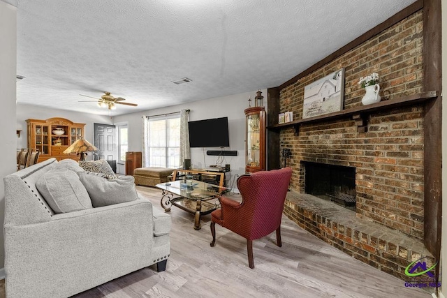 1322 Melford Dr, Columbus, GA 31907 - living room with a brick fireplace, a textured ceiling, light wood-style floors, and a ceiling fan