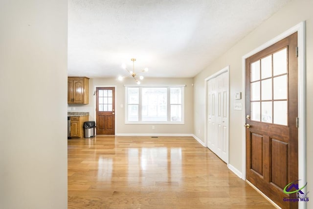 4407 Jones Rds, Macon, GA 31216 - foyer with light wood-type flooring, a chandelier, and baseboards