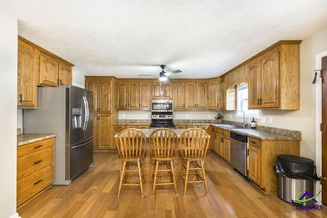 4407 Jones Rds, Macon, GA 31216 - kitchen featuring appliances with stainless steel finishes, a sink, brown cabinetry, and light wood finished floors