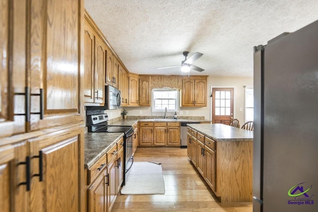 4407 Jones Rds, Macon, GA 31216 - kitchen featuring appliances with stainless steel finishes, a sink, light wood-type flooring, ceiling fan, and brown cabinetry