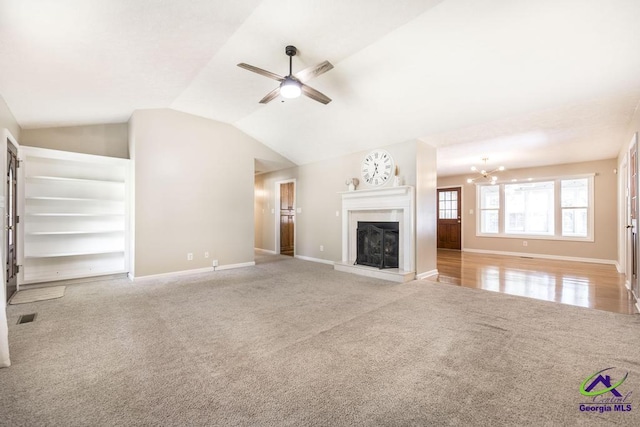 4407 Jones Rds, Macon, GA 31216 - unfurnished living room with carpet, a ceiling fan, baseboards, a fireplace with raised hearth, and a chandelier