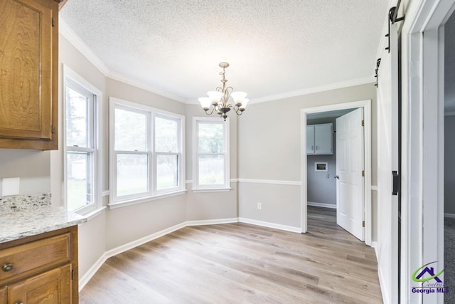 757 Silver Springs Drs, Macon, GA 31210 - unfurnished dining area with a textured ceiling, a chandelier, crown molding, light wood-style flooring, and a barn door