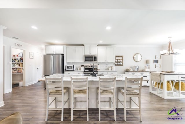 601 Hunts Landing Dr, Kathleen, GA 31047 - kitchen with stainless steel appliances, ornamental molding, a sink, an island with sink, and white cabinets