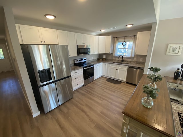 51 Cole Dr, Hawkinsville, GA 31036 - kitchen with appliances with stainless steel finishes, a sink, wood finished floors, white cabinets, and light stone counters